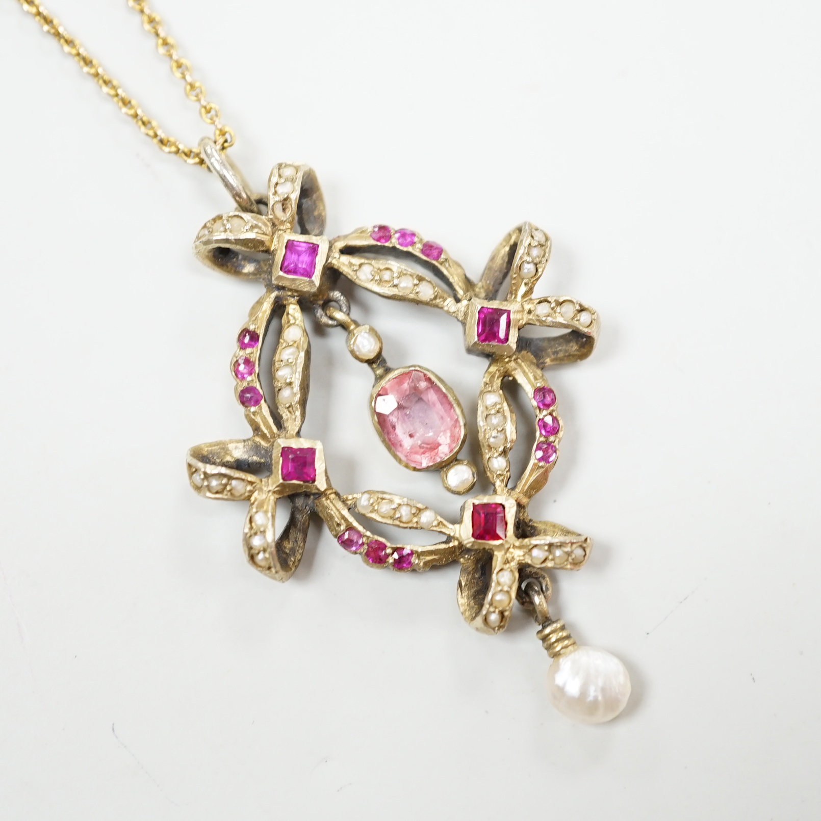 An early 20th century Continental gilt white metal pendant set with rubies, seed pearls and other gems, on a fine gold chain, leather cased, pendant 4.5cm